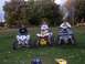 2001 Polaris TRAIL BLAZER - Three individuals pose on their ATVs in a grassy outdoor setting with trees in the background.