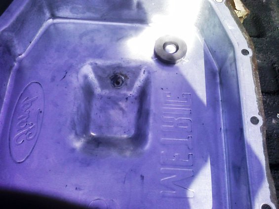 1117071044.jpg This picture shows the plug, drilled into the back part of the depression in the pan. Up is the back of the pan.

Started with a centerpunch and 1/8" hole, then I let it drain out. A little will still be in the pan. Remove pan, drill 1/2" hole (size may vary, read your plug instructions) 