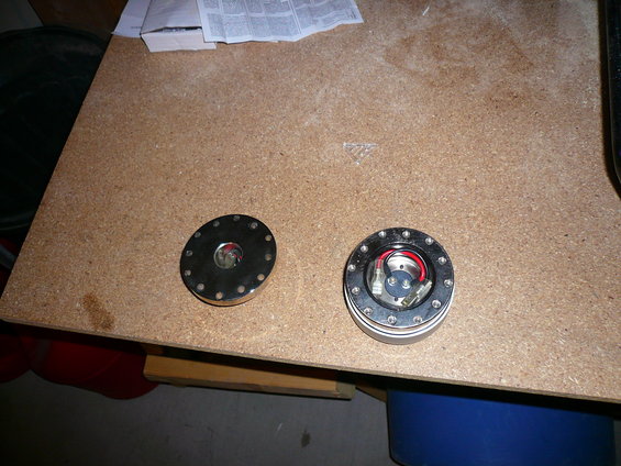 Two circular steering wheel hubs with bolts and wiring on a wooden surface