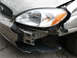 2004 Ford Taurus - The front of a 2004 Ford Taurus shows extensive damage, including a broken bumper and headlight assembly.