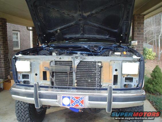 Blue SUV front end with hood open, showing grille and engine bay. Chrome bumper has a Confederate flag plate