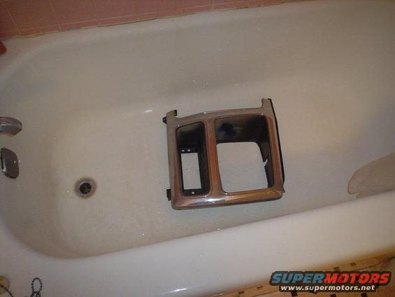 chrome trim piece with two rectangular openings sitting in a bathtub