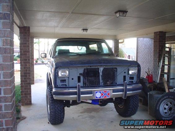 Dark blue SUV front view, missing grille and headlights, lifted suspension