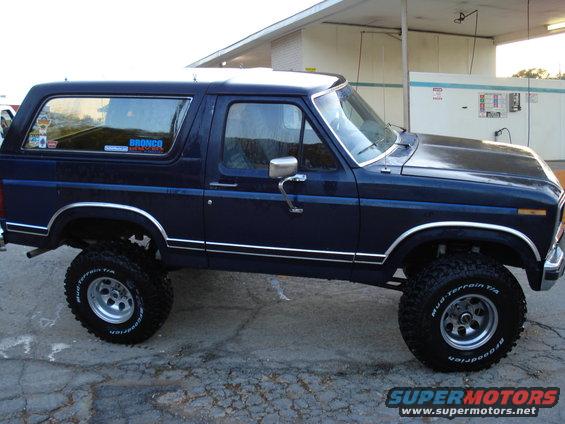 Dark blue Ford Bronco, lifted with off-road tires. Bronco sticker on rear window