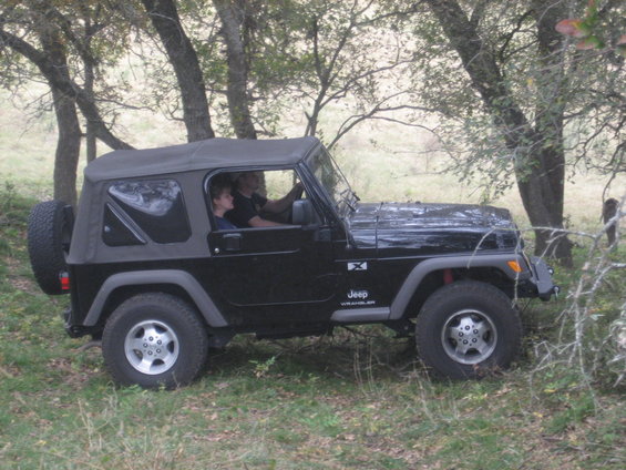 Black 2001 Jeep Wrangler side view with soft top and spare tire
