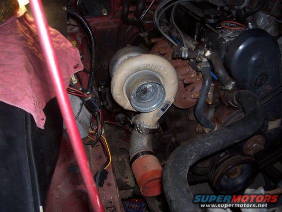Engine bay with a turbocharger, hoses, and wiring. A red cloth is draped over parts