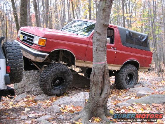 Red 1990 Ford Bronco navigating rocks, 3q-front view