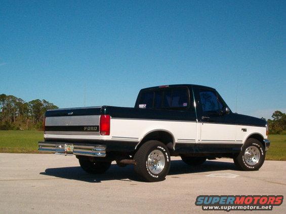Two-tone black and white Ford F-150 pickup truck, rear three-quarter view, chrome bumper, aftermarket wheels