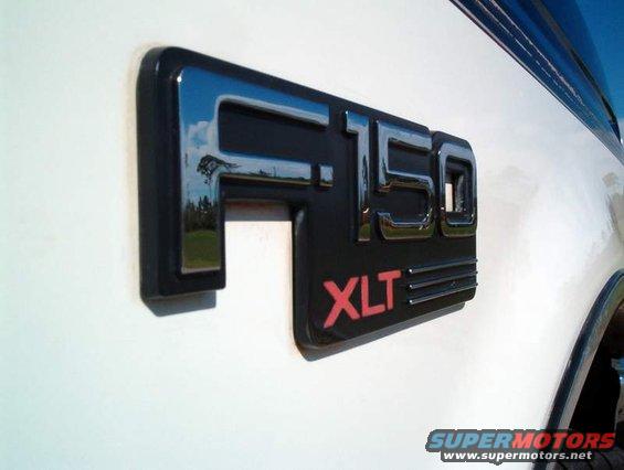 Close-up of a 1995 Ford F-150 XLT badge on a white truck