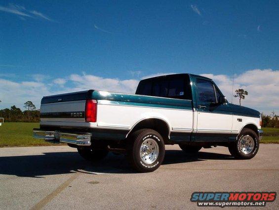 Two-tone green and white Ford F-150 truck, rear passenger side view, chrome bumper, aftermarket wheels