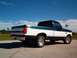 1995 Ford F-150 - A two-tone green and white Ford F-150 truck is parked on pavement under a clear blue sky.
