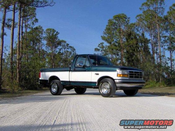 White and green 1995 Ford F-150 pickup truck parked on a dirt road