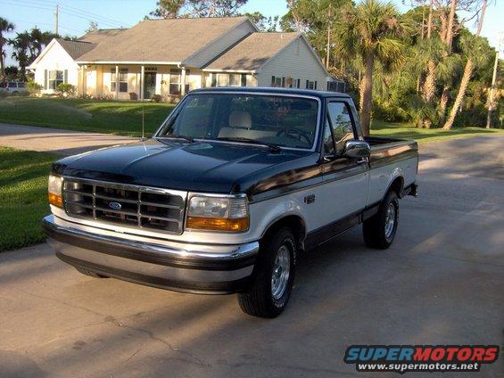 Two-tone blue and white Ford F-150 pickup truck, front 3/4 view, parked on driveway