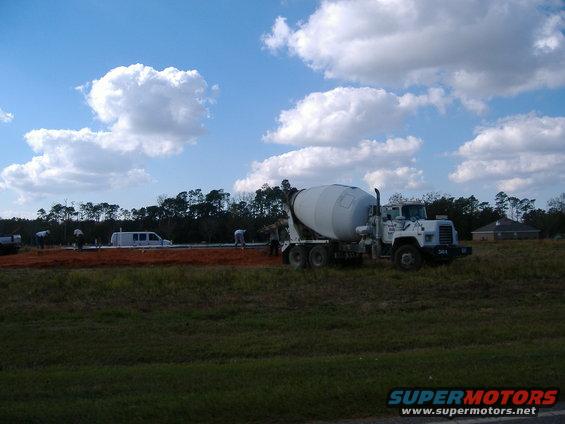 Concrete mixer truck and a van at a construction site with workers pouring concrete