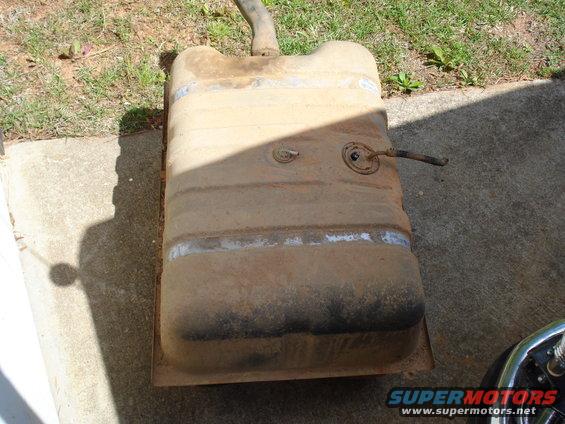 Old rusty fuel tank with a pipe sticking out, sitting on concrete