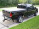 1994 Ford F-250 - This black pickup truck has a tonneau cover and a "4x4" decal on the fender.