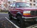 1994 Ford Bronco - A maroon 1994 Ford Bronco is parked in a lot with fallen leaves on the ground.