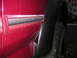 1994 Ford Bronco - Detail of a red SUV's bodywork, focusing on the fender flare and a chrome trim strip.