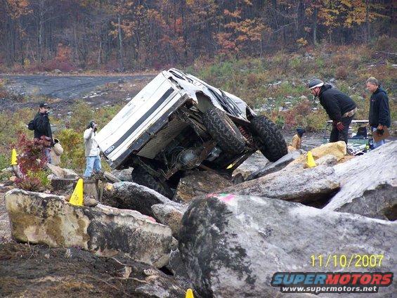 White 1995 Ford Bronco tipped on its side on rocks during an off-road event
