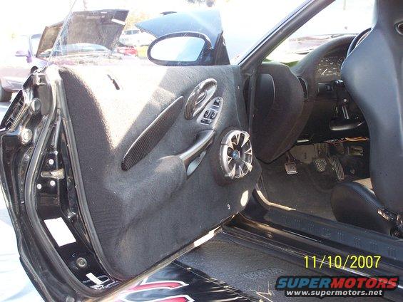 Car interior door panel with aftermarket speaker and carbon fiber trim, driver's side
