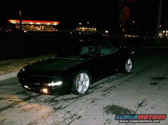 Black sports car parked at night near a gas station