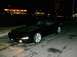 1995 Ford Probe - A black sports car is parked on a wet road at night, with a gas station in the background.