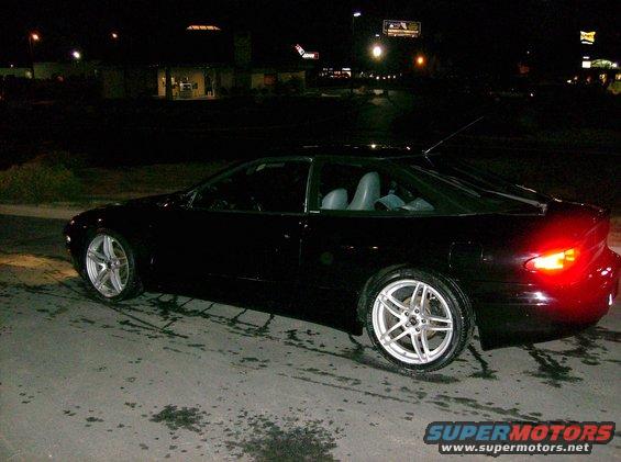 Black coupe with aftermarket wheels parked at night