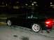 1995 Ford Probe - A black coupe with aftermarket wheels is parked on a wet surface at night.