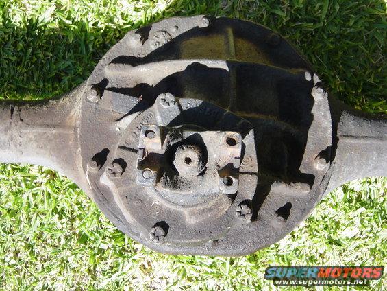 Rear axle differential housing with drive shaft attached, resting on grass