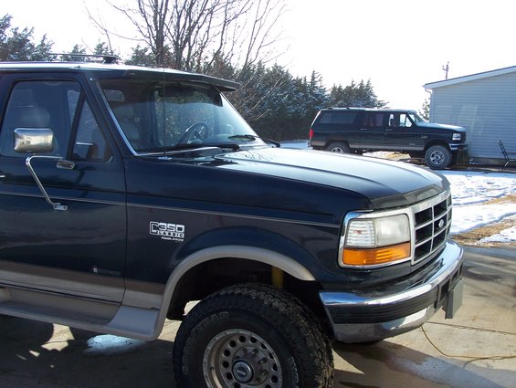Dark blue Ford F-Series truck, front quarter view. Another dark SUV is parked behind it