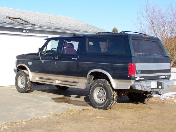 Dark blue and tan SUV with aftermarket bumper and roof rack, parked in driveway