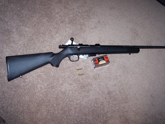 Black rifle with box of ammunition and two loose cartridges