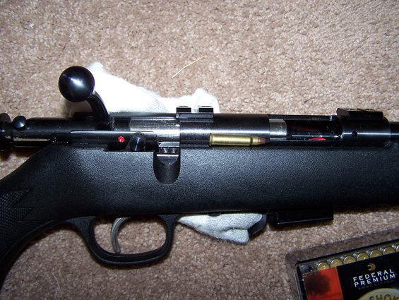 Close-up of a rifle action with a round in the chamber and a box of Federal Premium ammunition