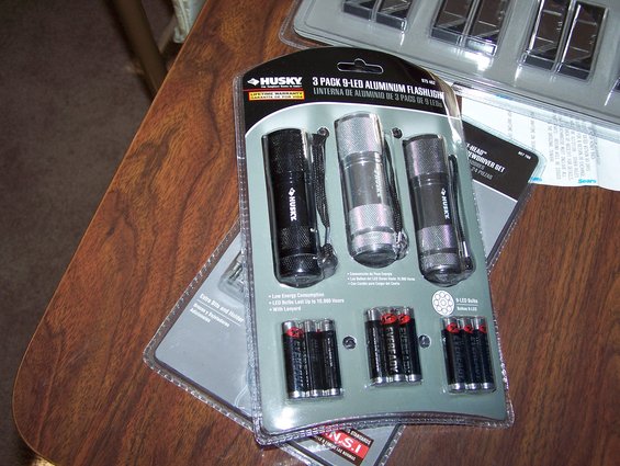 Husky 3-pack aluminum flashlights with batteries on a wooden table