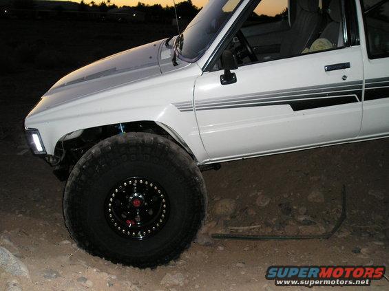 White pickup truck with black stripe decals, lifted suspension, and off-road tires