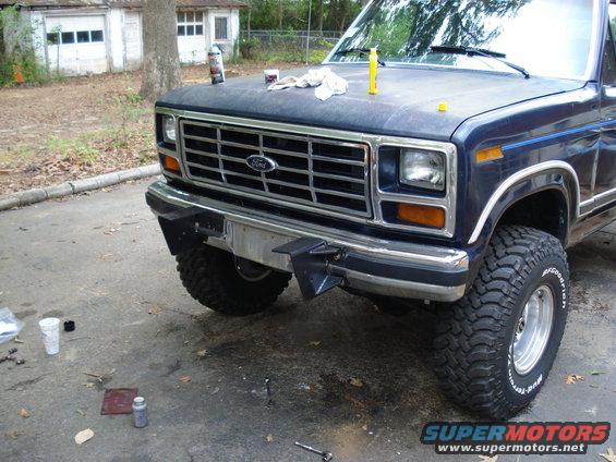 Front view of a dark blue Ford truck with a chrome grille and aftermarket bumper. BFGoodrich Mud-Terrain tires are visible