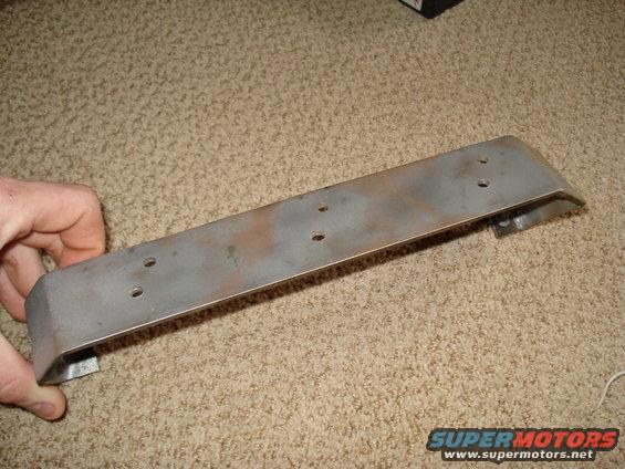 Metal bracket with mounting holes, held by a hand