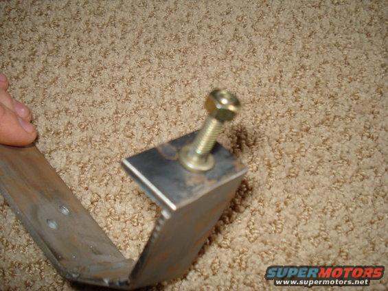 Metal bracket with a bolt and washer attached to a carpeted surface