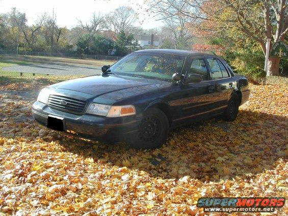 Dark sedan parked on fallen leaves, front quarter view. Black steel wheels, police-style mirrors