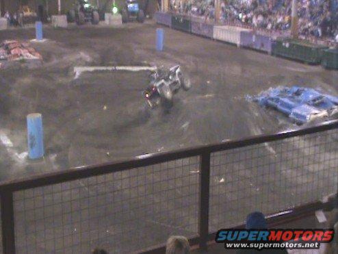 Monster truck doing a stunt in an arena with spectators in the background