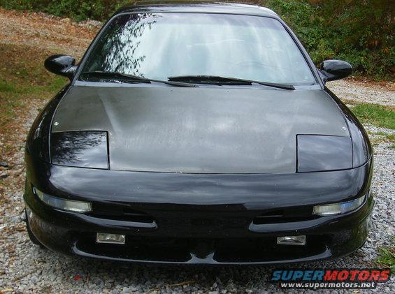 Black car with pop-up headlights and a matte grey hood, viewed from the front