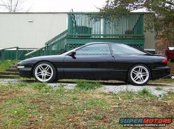 Black Ford Probe parked outside a trailer with a green deck