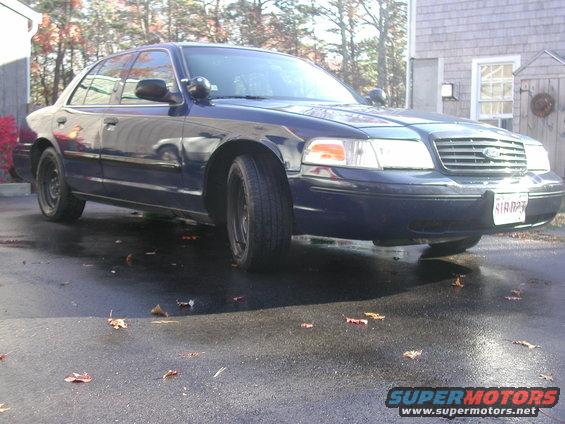 Dark blue Ford Crown Victoria parked on wet asphalt, front quarter view