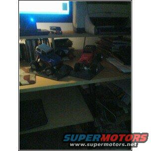 Two toy trucks, one blue and one red, on display shelves