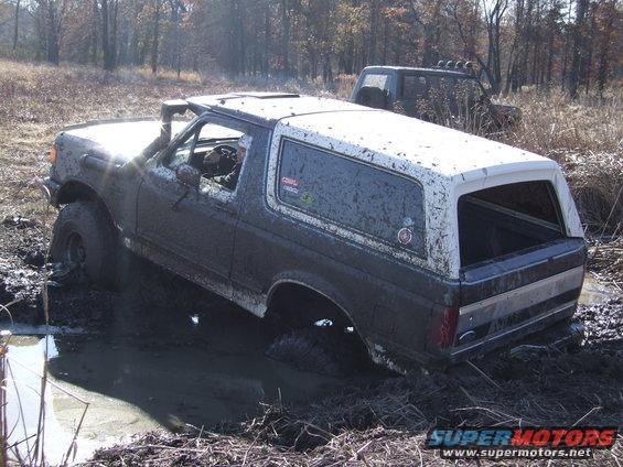 Mud-covered SUV stuck in mud with another vehicle behind it