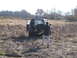 1979 Ford Bronco - A person attempts to free a vehicle that is stuck in a field with dry vegetation.