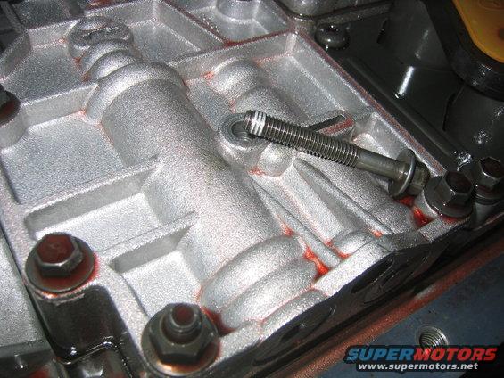 Transmission pan interior with red fluid residue and a bolt with a washer
