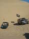 1994 Ford Bronco - Two SUVs, including a 1994 Ford Bronco, navigate sandy terrain with flags flying.