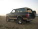 1994 Ford Bronco - A two-tone Ford Bronco sits on a sandy beach with the ocean in the background.