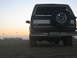 1994 Ford Bronco - Rear view of a 1994 Ford Bronco on the beach at sunset, with RVs and flags visible.